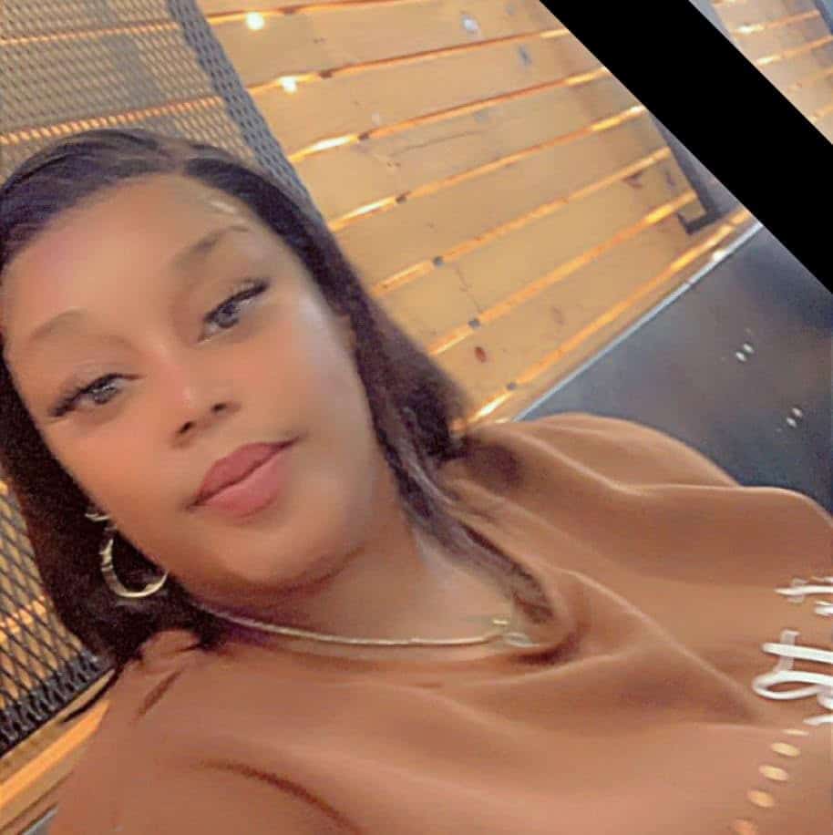 A woman with dark hair and hoop earrings enjoying a relaxed moment outdoors at sunset.