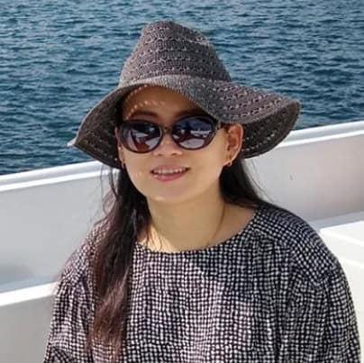Woman in sunhat and sunglasses on boat, enjoying sunny day.
