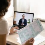 Woman consulting with a tax expert via video call while reviewing tax documents.