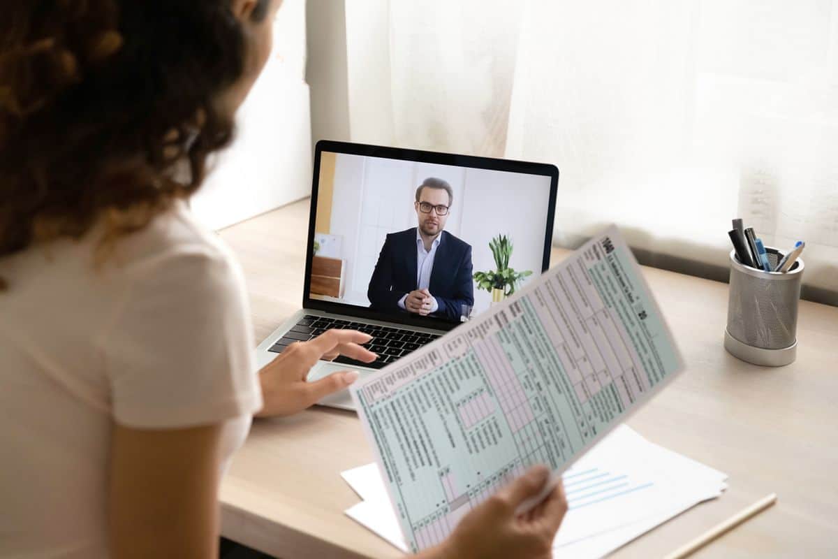 Woman consulting with a tax expert via video call while reviewing tax documents.