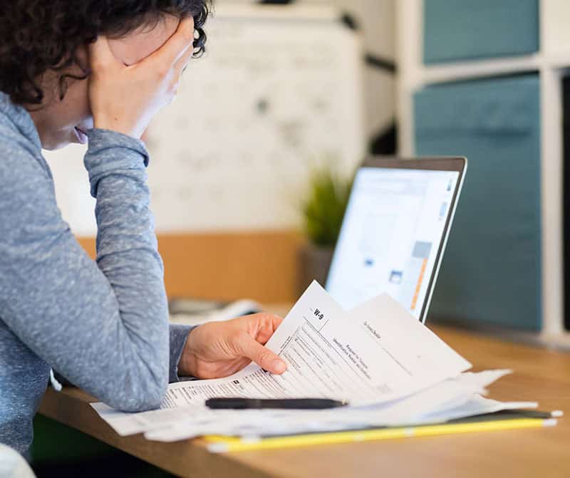 Person reviewing tax documents with a laptop, focusing on tax credits and deductions.